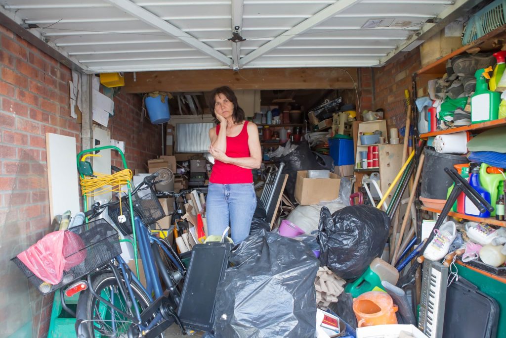 Frustrated-woman-standing-in-a-messy-garage-wondering-how-to-start-getting-an-organized-garage